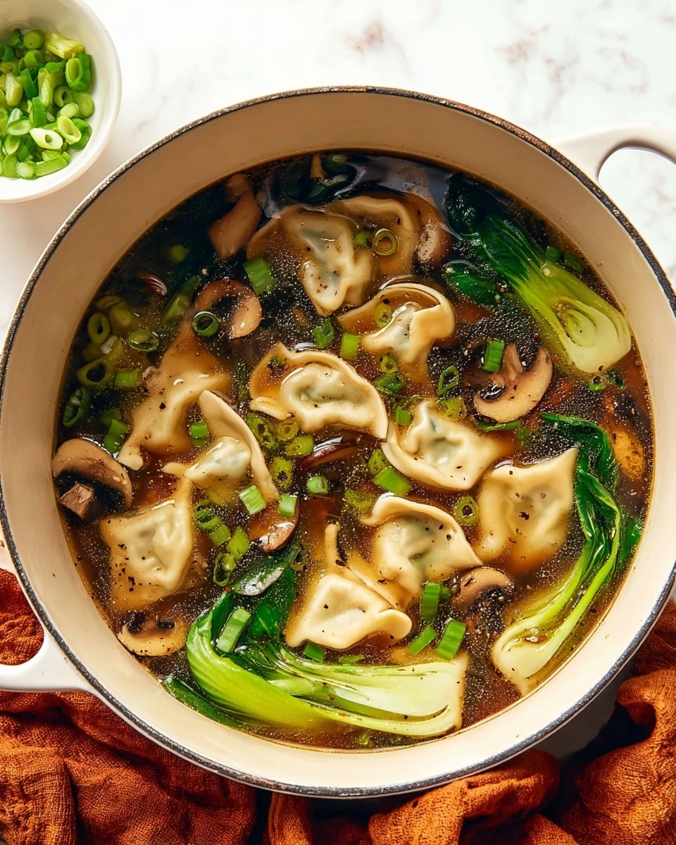 A large white pot filled with a clear dark brown broth containing several light beige dumplings with soft, folded edges, green bok choy with smooth, shiny leaves and thick stems, slices of dark brown shiitake mushrooms, and small round slices of bright green scallions scattered on top. The soup has specks of black pepper floating on the surface. The pot is placed on a soft, crumpled burnt orange cloth, and a small white bowl with chopped green scallions is visible in the background on a white marbled surface. photo taken with an iphone --ar 4:5 --v 7