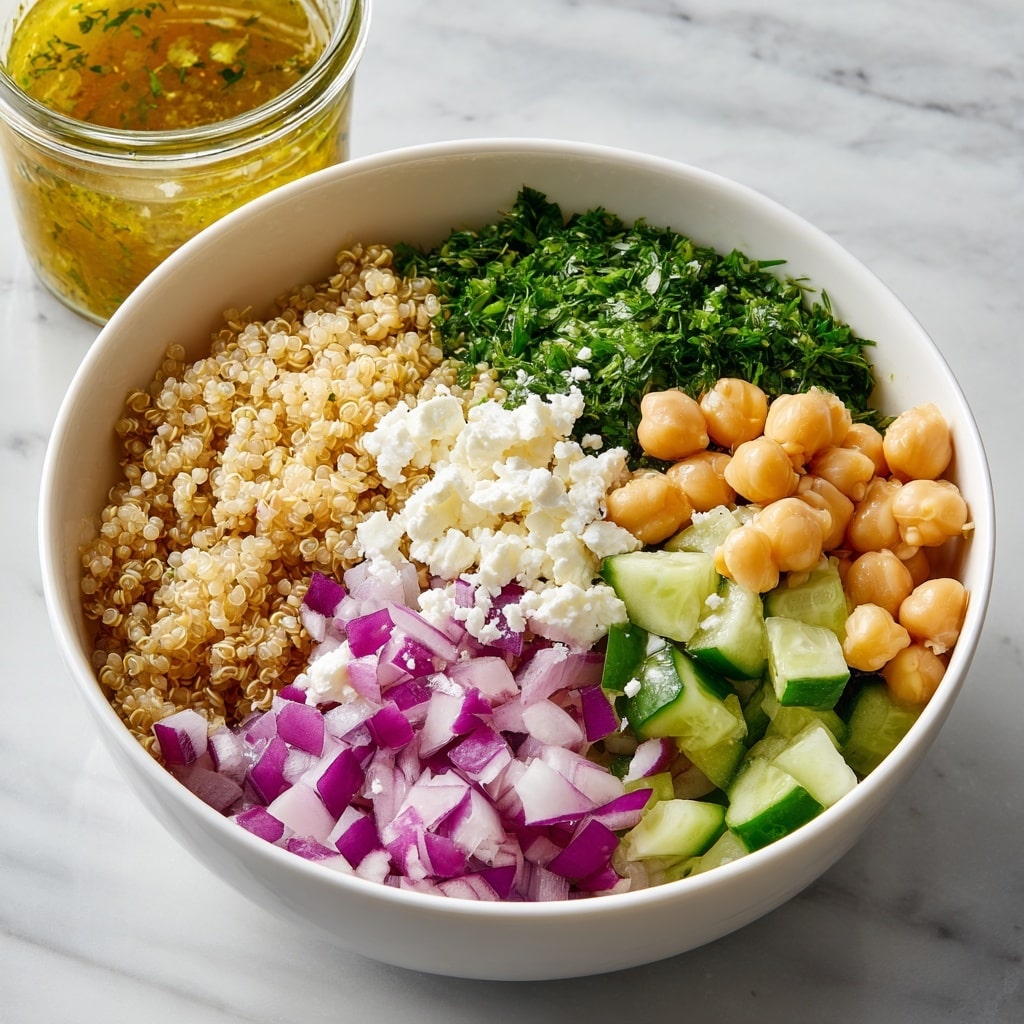 A white bowl filled with six visible layers of fresh ingredients arranged side by side. Starting from the left, there are light beige chickpeas with a smooth texture, next a pile of finely chopped dark green parsley with a leafy texture, followed by a heap of light beige cooked quinoa with a grainy texture. Continuing clockwise, there is a mound of white, crumbly feta cheese, then fresh cucumber chunks with green skin and pale green flesh, and finally diced purple and white red onions. In the background, a glass jar with orange-yellow dressing, lemon halves, and a white plate with more parsley and red onion are placed on a white marbled surface. Photo taken with an iphone --ar 4:5 --v 7