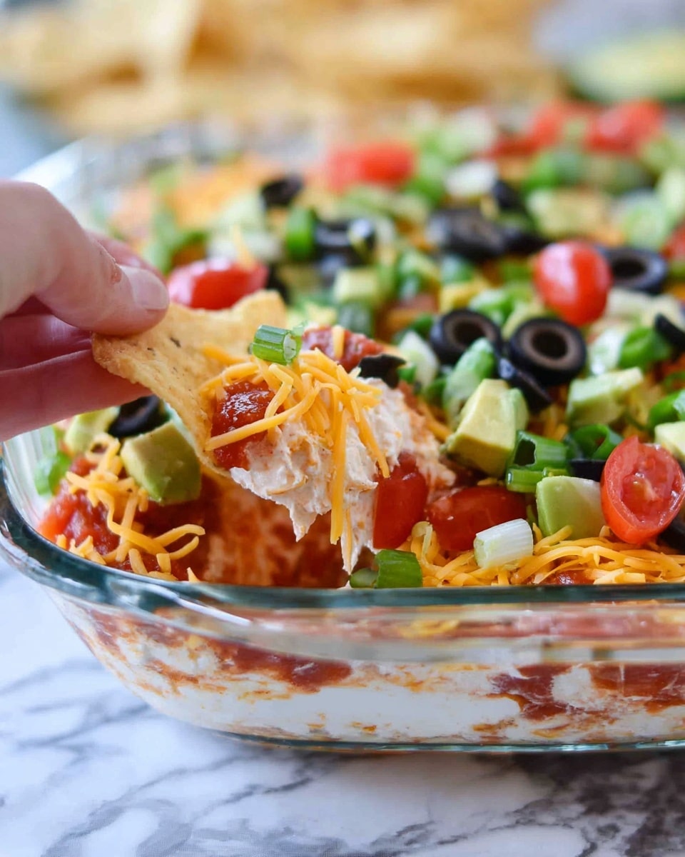 This image shows a layered salad in a clear glass rectangular dish. The bottom layer appears to be light green lettuce leaves, topped with a second layer of diced light green cucumbers and bright red tomato chunks. Scattered on top are small black olive slices and shredded orange cheddar cheese, creating a colorful contrast with the greens and reds. The vegetables and cheese are unevenly spread, showing some fresh texture and making the salad look full and fresh. The dish is placed on a white marbled surface, and the photo is taken close up, focusing on the colorful ingredients. photo taken with an iphone --ar 4:5 --v 7