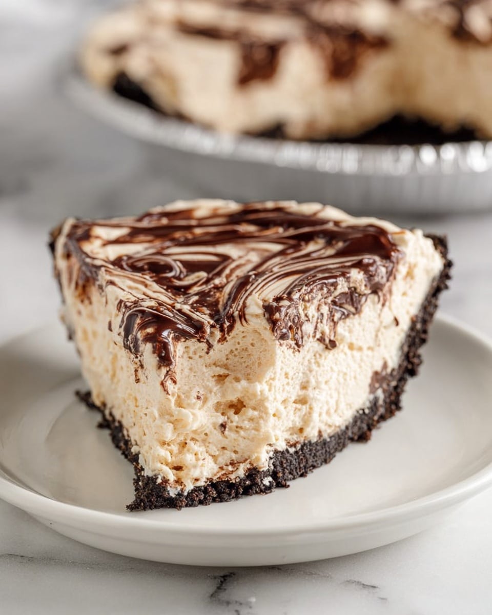 The image shows a creamy dessert pie with three clear layers: a dark brown, crumbly crust forming the base and sides; a thick, light beige, smooth and fluffy filling in the middle; and a marbled top layer with swirled dark chocolate and light cream colors, creating a glossy and rich pattern. A slice has been cut out and is held by a woman's hand using a metal pie server. The pie sits in a shiny silver foil pan on a white marbled surface. Photo taken with an iphone --ar 4:5 --v 7