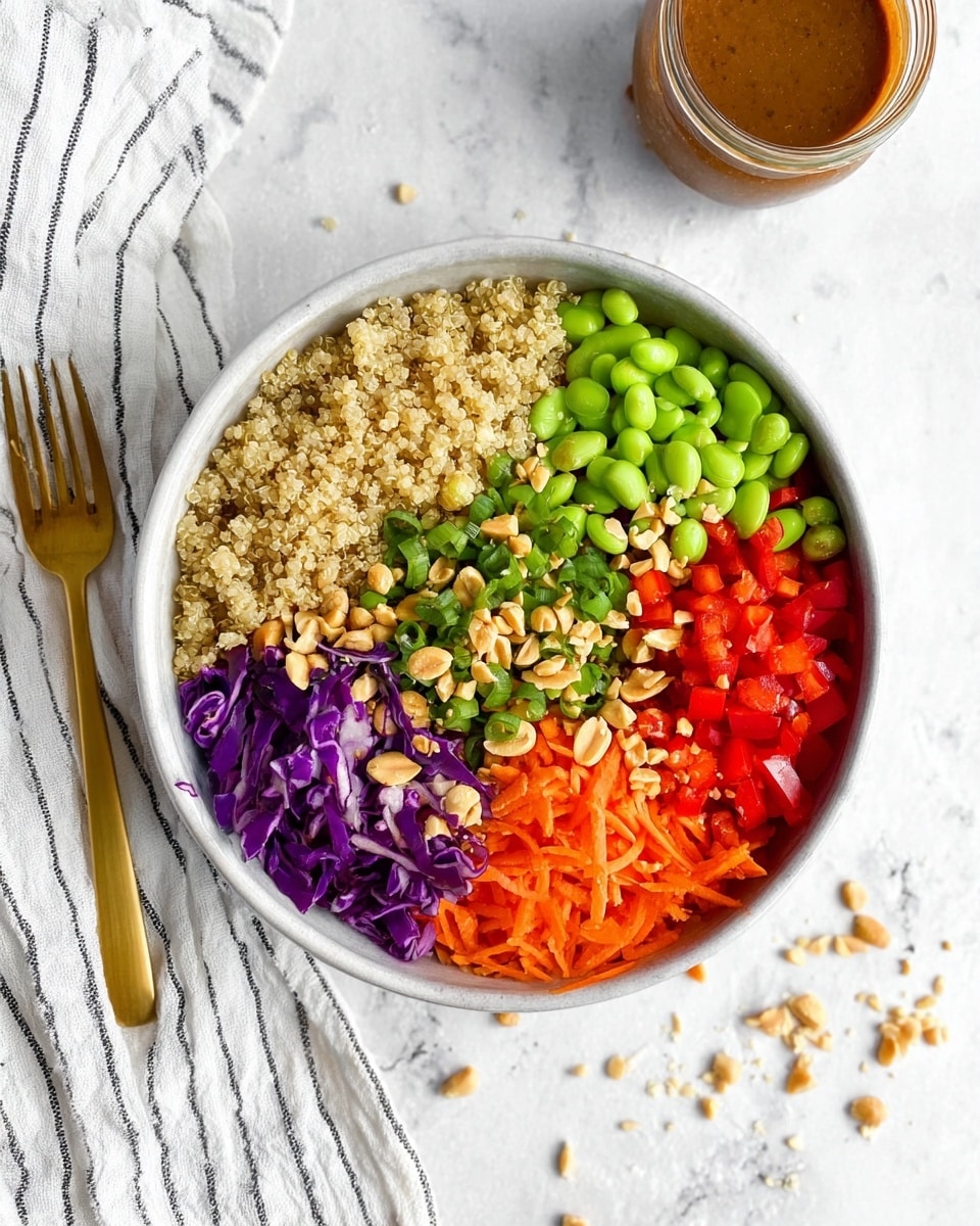 A white speckled bowl with a dark rim holds a colorful quinoa salad. The base layer is light beige cooked quinoa, mixed with bright green edamame beans, small orange carrot pieces, and tiny bits of purple cabbage. Over this mix, there are fresh green herb leaves scattered around, along with chopped peanuts adding a light brown crunchy texture. A glossy, brown dressing is drizzled generously on top, with some dressing pooling slightly. The bowl is set on a white marbled surface with some crushed peanuts scattered nearby, and a gold fork rests on a white-striped cloth to the left side. photo taken with an iphone --ar 4:5 --v 7