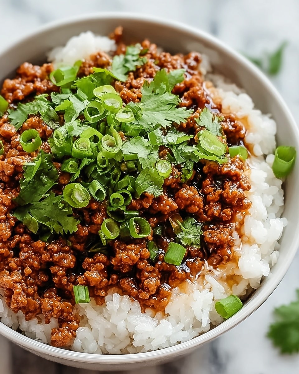 A close-up view of a two-layered bowl meal with the bottom layer filled with fluffy white rice that has a soft and grainy texture, topped with a generous layer of glossy, brown minced meat coated in a thick, shiny sauce. On top of the meat, bright green chopped scallions and fresh cilantro leaves are scattered evenly, adding a pop of color and freshness. The bowl itself is white, and the photo is set against a white marbled texture, giving a clean and simple look. Photo taken with an iphone --ar 4:5 --v 7