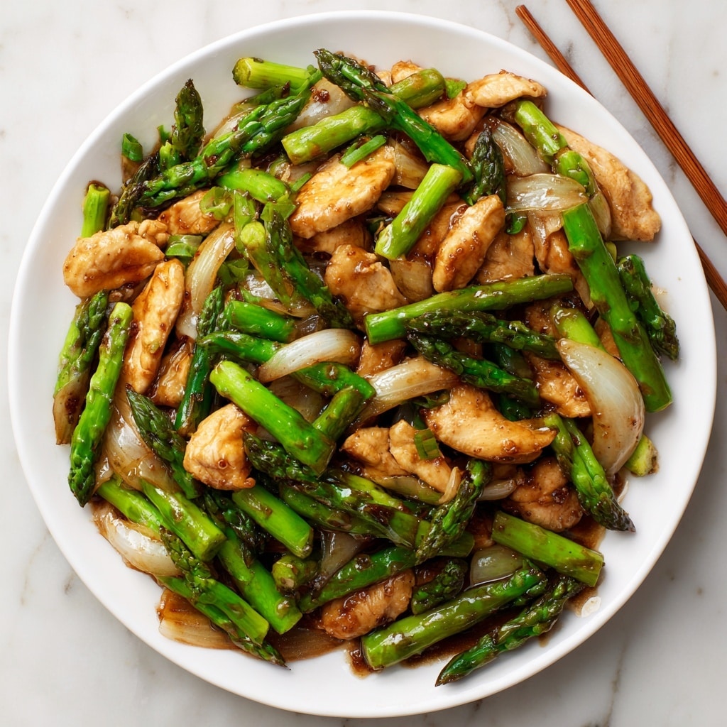 A white plate filled with a stir-fry dish featuring three main layers: the bottom layer has sliced onions with a pale translucent color, the middle layer has bright green asparagus spears with a slightly glossy texture, and the top layer contains golden brown cooked chicken slices with a slightly shiny surface from the sauce. Next to the plate, there is a bowl of white rice topped with small pieces of chopped green onions. Brown wooden chopsticks lie beside the plate on a white marbled surface. In the background, a beige ceramic pot with a white lid and a blue floral design adds a soft touch. photo taken with an iphone --ar 4:5 --v 7